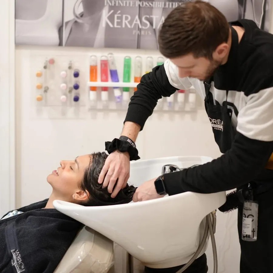 A stylist washing a client's hair at the basin